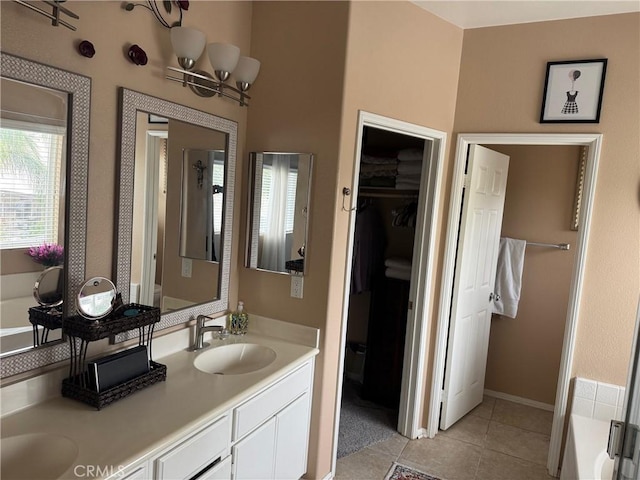 bathroom with a bathing tub, a walk in closet, tile patterned floors, and a sink
