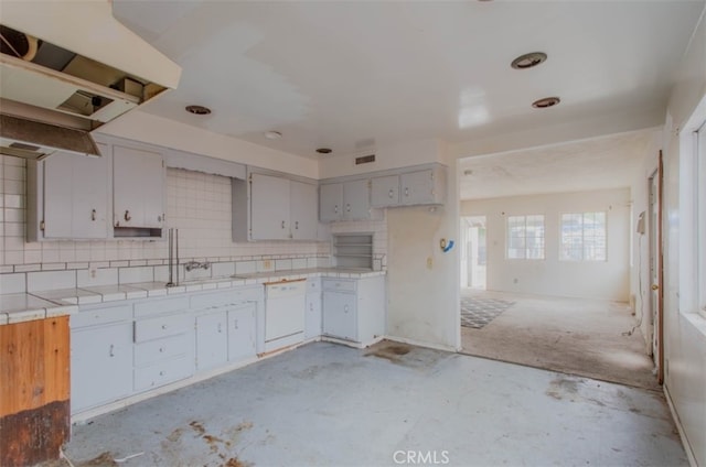 kitchen with decorative backsplash, dishwasher, concrete floors, open floor plan, and tile counters