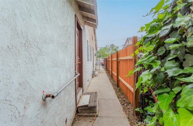 view of side of home with stucco siding and fence