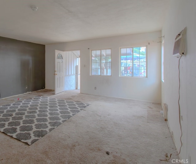 spare room featuring a wall mounted AC and carpet flooring