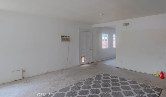 spare room with carpet flooring, an AC wall unit, and visible vents