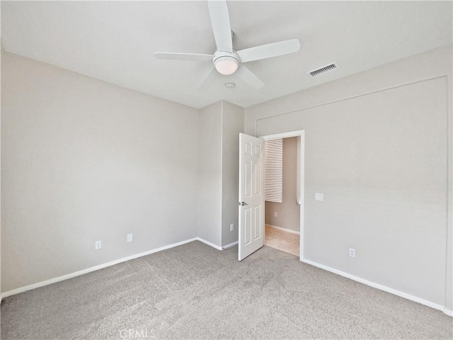 carpeted empty room featuring baseboards, a ceiling fan, and visible vents