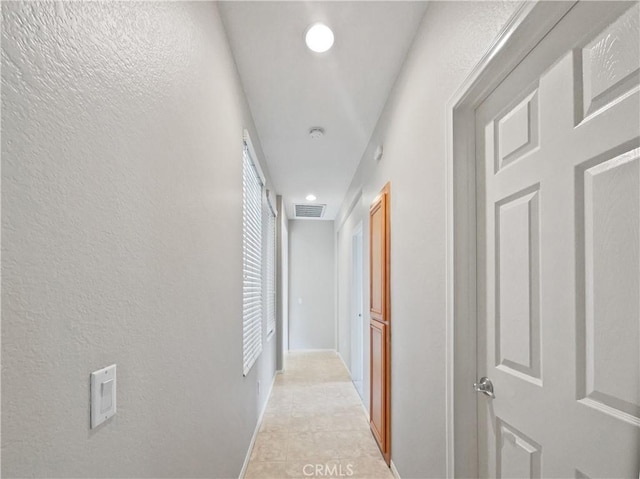hallway with recessed lighting, a textured wall, and visible vents