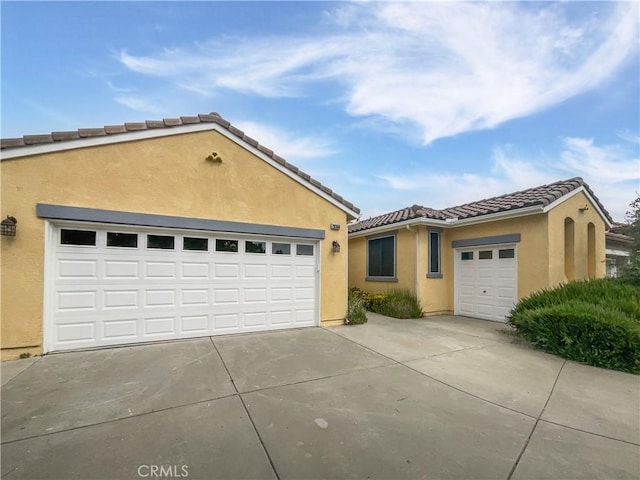 single story home featuring a garage, stucco siding, driveway, and a tile roof