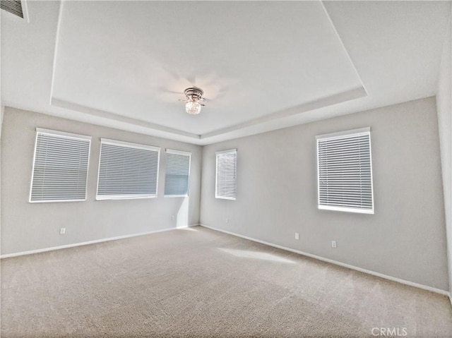 unfurnished room with visible vents, baseboards, ceiling fan, and a tray ceiling