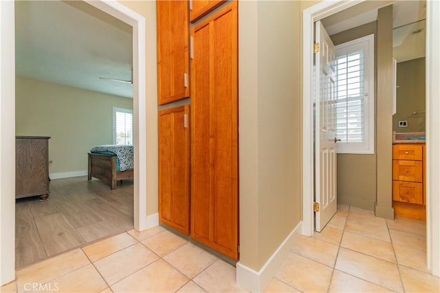 corridor featuring light tile patterned floors and baseboards
