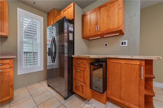 kitchen with light countertops, brown cabinetry, wine cooler, and black refrigerator with ice dispenser