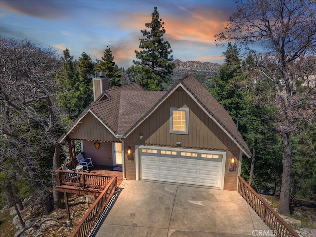 1119 Brentwood Dr, Lake Arrowhead, CA 92352 - view of front of home featuring roof with shingles, an attached garage, board and batten siding, a chimney, and driveway