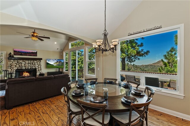 1119 Brentwood Dr, Lake Arrowhead, CA 92352 - dining room featuring a stone fireplace, arched walkways, vaulted ceiling, light wood-type flooring, and ceiling fan with notable chandelier