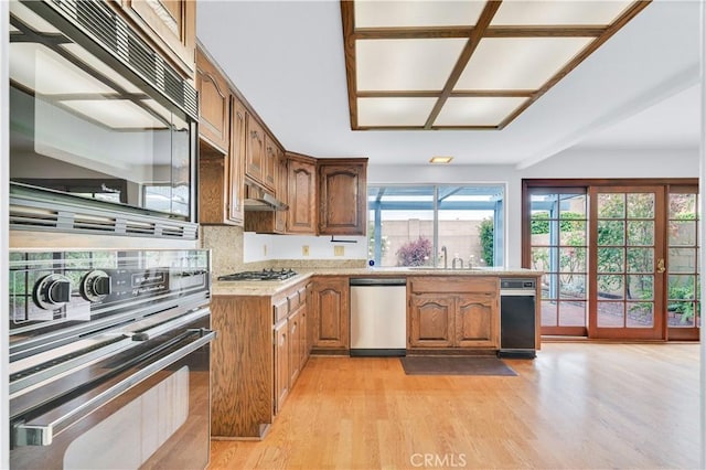 8913 La Dona Ct, Fountain Valley, CA 92708 - kitchen featuring brown cabinetry, a sink, light wood finished floors, under cabinet range hood, and stainless steel appliances