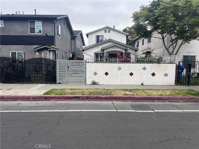 view of front facade featuring a fenced front yard, a gate, and stucco siding