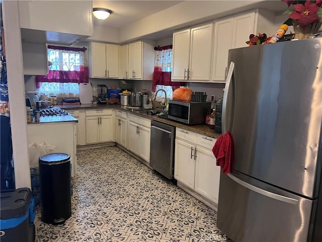 kitchen featuring a sink, appliances with stainless steel finishes, white cabinetry, and a wealth of natural light