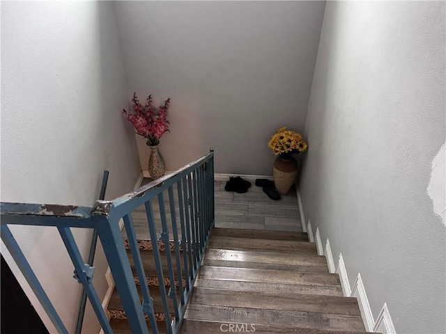 staircase featuring baseboards and wood finished floors