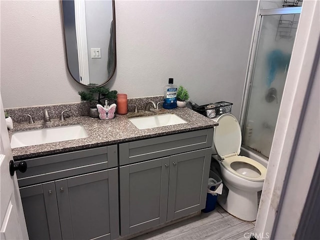 bathroom featuring double vanity, toilet, a sink, and wood finished floors