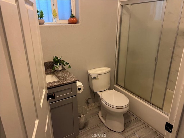 full bathroom featuring vanity, combined bath / shower with glass door, and toilet