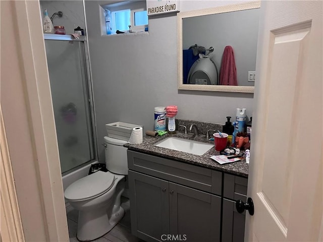 bathroom featuring vanity, bath / shower combo with glass door, tile patterned flooring, and toilet