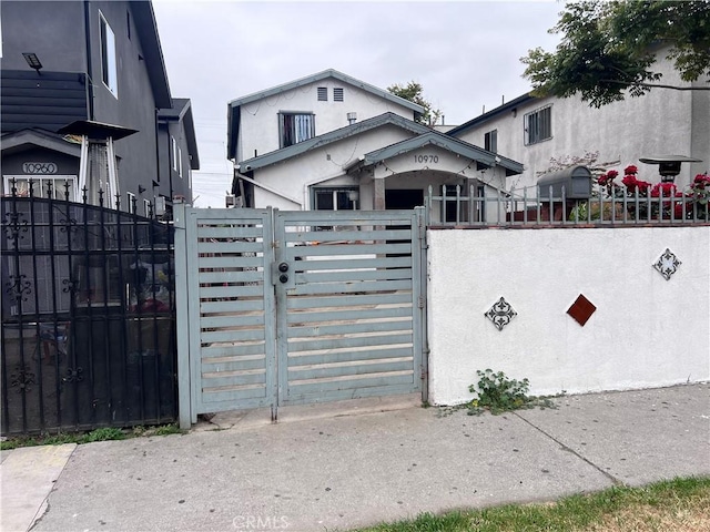 view of front of house featuring a gate, stucco siding, and fence private yard