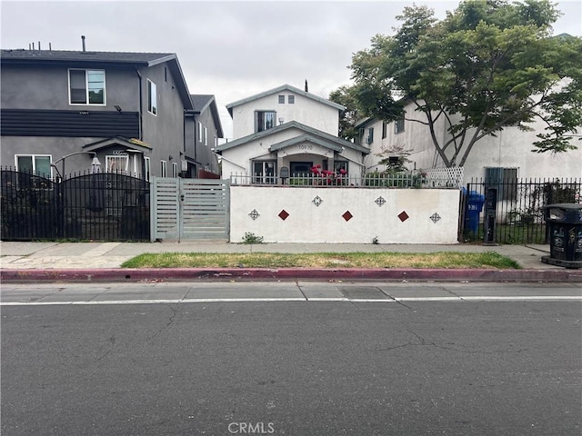 view of front of house with fence, a gate, and stucco siding