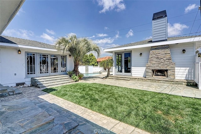 back of house featuring an outdoor stone fireplace, a patio area, and french doors
