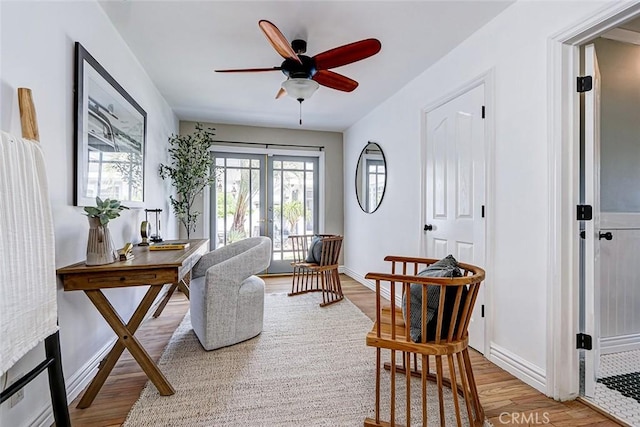 sitting room with french doors, a ceiling fan, light wood finished floors, and baseboards