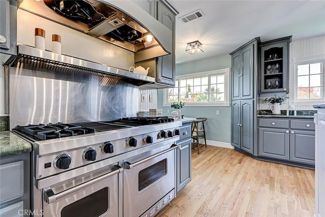 kitchen featuring gray cabinetry, double oven range, a wealth of natural light, and visible vents