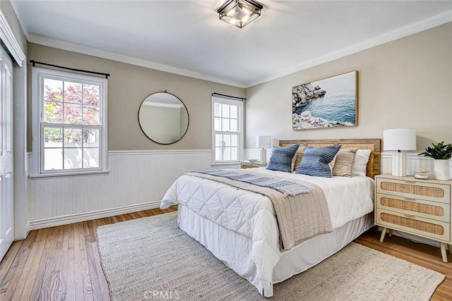 bedroom featuring ornamental molding, wainscoting, and wood finished floors