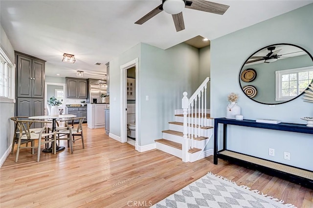 interior space with baseboards, a ceiling fan, light wood-style flooring, and stairway