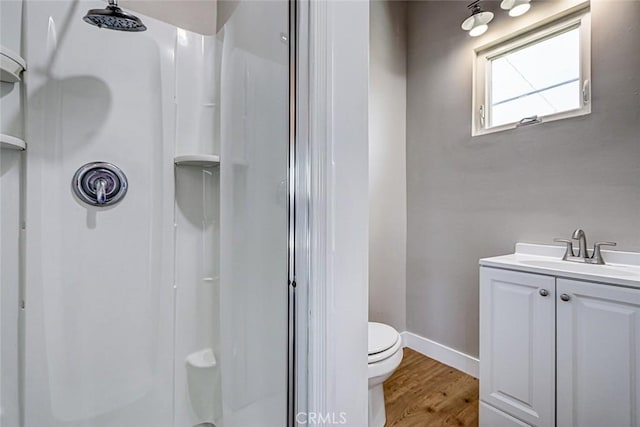 bathroom with toilet, a shower stall, and wood finished floors