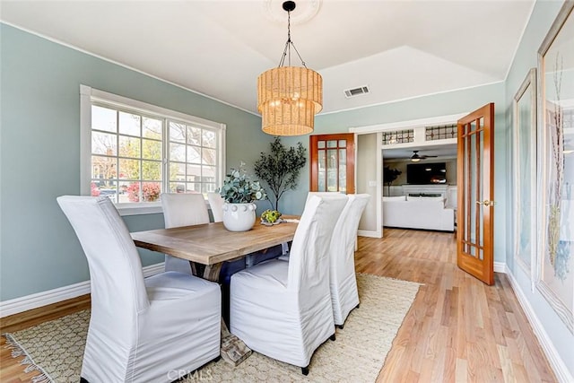 dining room featuring vaulted ceiling, a chandelier, light wood-style flooring, and visible vents