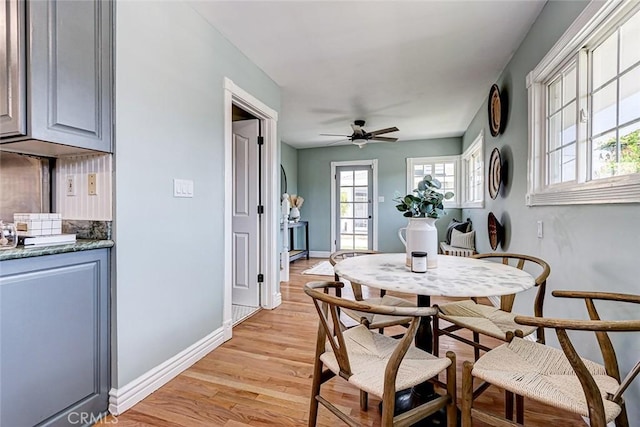 dining room featuring baseboards, a ceiling fan, and light wood-style flooring