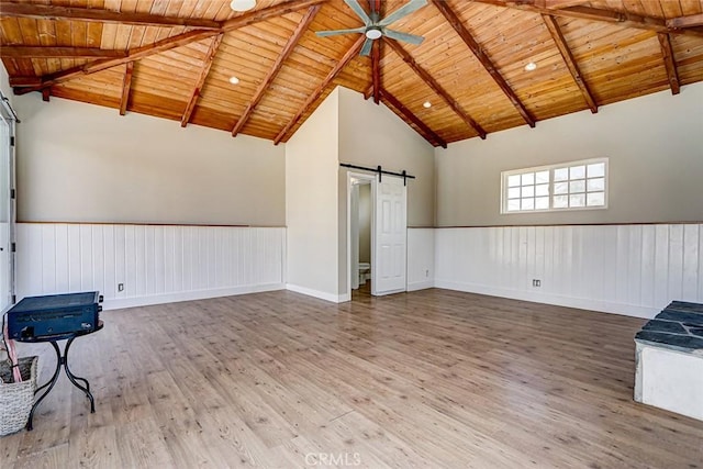 empty room featuring wooden ceiling, a ceiling fan, a barn door, and wood finished floors