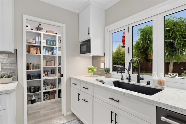 interior space with a sink, stainless steel dishwasher, black microwave, and backsplash