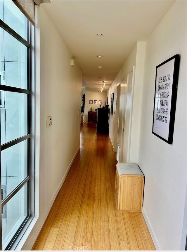hallway featuring light wood-style floors, recessed lighting, and baseboards