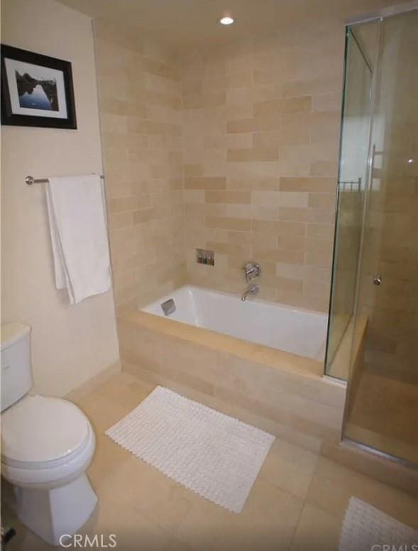 full bathroom with tile patterned flooring, a washtub, a shower with door, and toilet