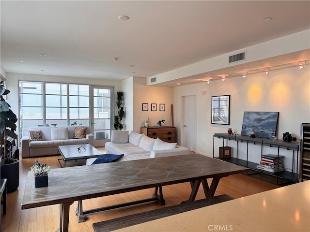 living room with rail lighting, wood finished floors, and visible vents