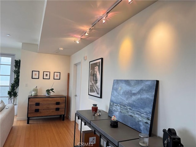 hall with rail lighting, baseboards, and light wood-style floors