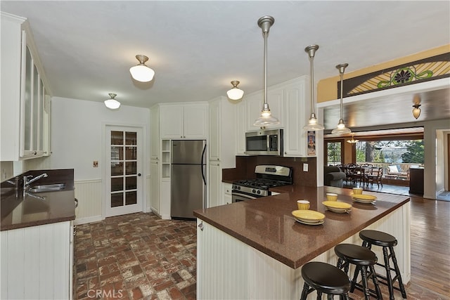 242 Holiday Dr, Lake Arrowhead, CA 92352 - kitchen with a peninsula, dark countertops, white cabinetry, a sink, and stainless steel appliances