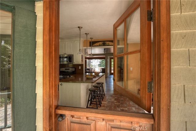 242 Holiday Dr, Lake Arrowhead, CA 92352 - interior space with dark countertops, a kitchen breakfast bar, brick floor, appliances with stainless steel finishes, and decorative light fixtures