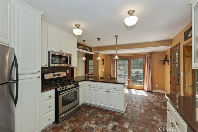 242 Holiday Dr, Lake Arrowhead, CA 92352 - kitchen with appliances with stainless steel finishes, a peninsula, dark countertops, and brick floors
