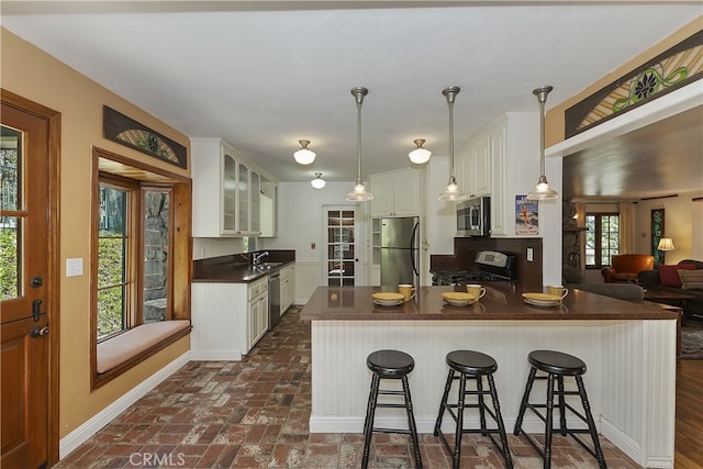242 Holiday Dr, Lake Arrowhead, CA 92352 - kitchen featuring white cabinets, dark countertops, brick floor, stainless steel appliances, and glass insert cabinets