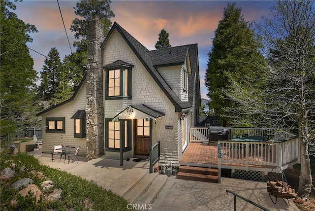 242 Holiday Dr, Lake Arrowhead, CA 92352 - back of house at dusk with a patio, a chimney, roof with shingles, and a deck