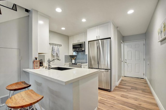385 E Surfside Dr, Port Hueneme, CA 93041 - kitchen with a sink, white cabinets, a peninsula, stainless steel appliances, and light wood-style flooring