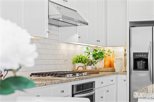 kitchen featuring white cabinets, backsplash, stainless steel appliances, and under cabinet range hood