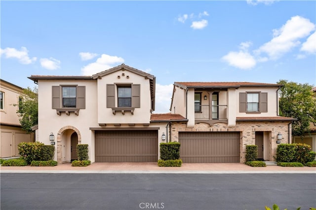 view of front of house featuring a garage, stucco siding, decorative driveway, and a balcony
