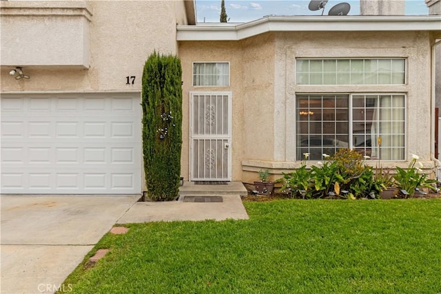 doorway to property with stucco siding, a lawn, and concrete driveway