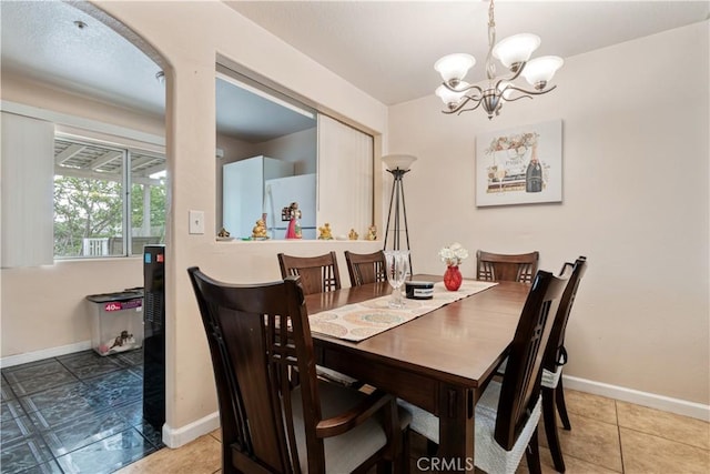 tiled dining space featuring a chandelier and baseboards
