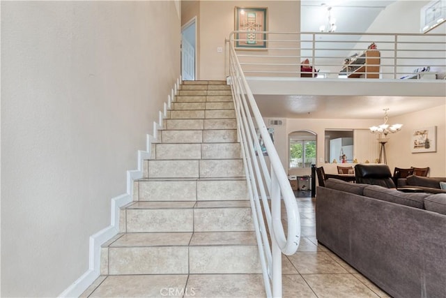 staircase featuring a chandelier, tile patterned flooring, arched walkways, and baseboards