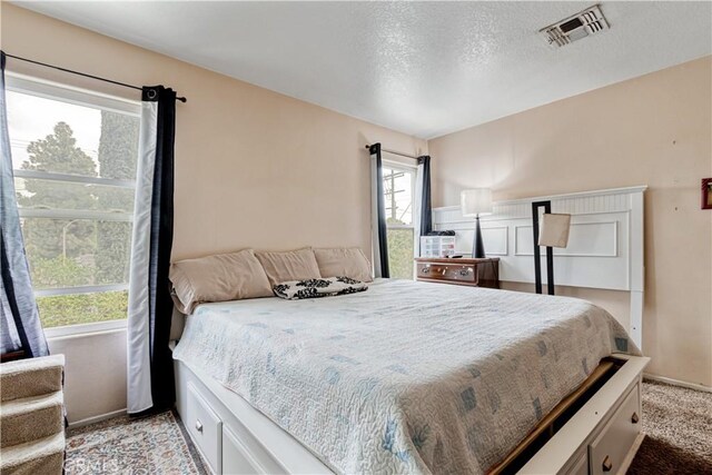 bedroom featuring light carpet, a textured ceiling, and baseboards