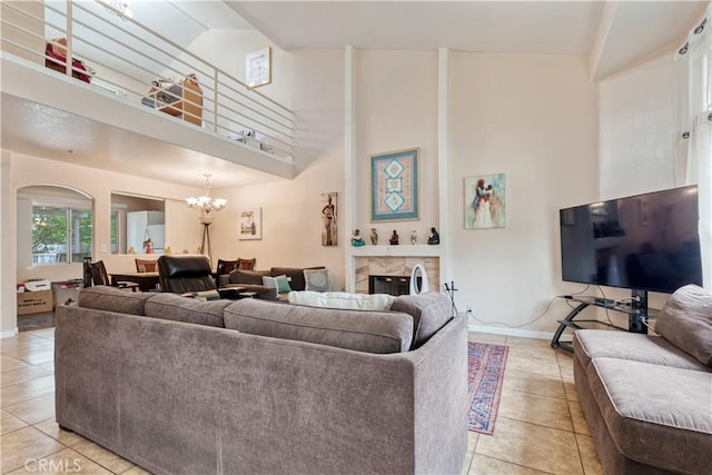living area with light tile patterned floors, a chandelier, a towering ceiling, baseboards, and arched walkways