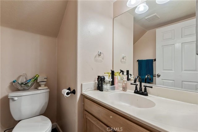 bathroom with lofted ceiling, toilet, and vanity